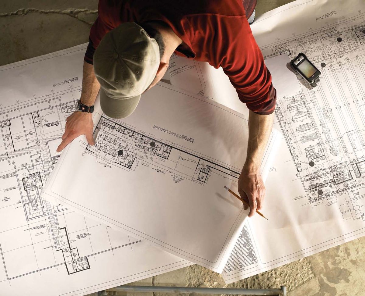 A Setronics engineer marking up building plans on site