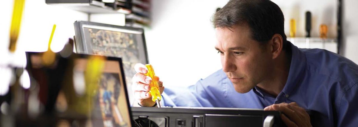 A technician repairing security equipment at a workbench